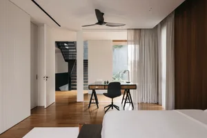 A minimalist residential bedroom featuring wooden flooring, glass windows, fabric curtains, and metal furniture.