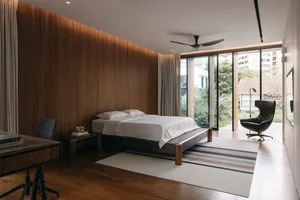 A modern minimalist bedroom featuring wood walls and a view of the outdoors.