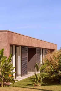 Modern residential exterior featuring concrete walls and metal shuttered windows.