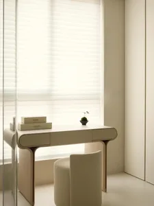 A minimalist home office desk with a white finish and modern design features a sleek, curved shape and a single drawer.