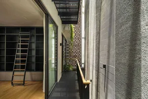Modern indoor space featuring wooden flooring, metallic railings, glass walls, and concrete structural elements.