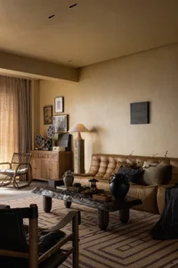 A living room with a brown leather sofa, dramatic lighting, and wooden accents.