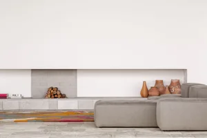 A minimalist living room featuring concrete furniture and soft textiles.