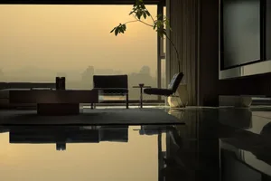 A minimalist living room with dark wood flooring, a large window, a plant, a couch, and two armchairs.