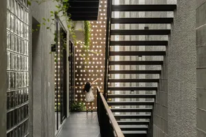 A modern industrial staircase with a metal frame, glass walls, and a child playing on the landing.