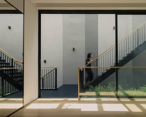 A modern interior design featuring a glass staircase with a person walking.