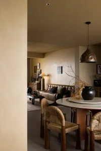 Modern living room featuring a marble table, leather sofa, and woven chairs.