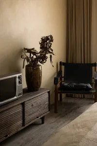 A living room featuring a wooden sideboard, a black armchair, and a vintage television.