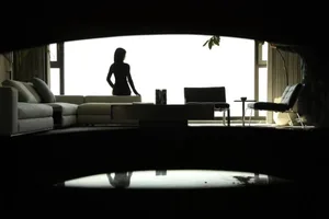 A modern living room with glass walls, a sleek sofa, and minimalist decor.