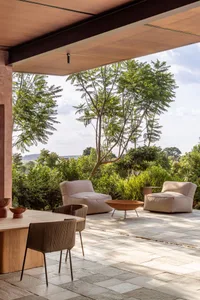 Modern outdoor living space featuring comfortable cushions and a fire pit surrounded by greenery.