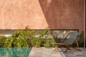Modern residential lounge featuring concrete walls and a green poolside garden.