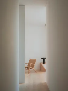 A minimalist interior with a wooden chair against a wall.