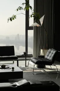 A sleek, minimalist living room featuring leather furniture, marble accents, and a glass coffee table.