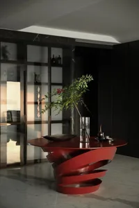 Modern living room featuring a red metallic twist table with a potted plant and decorative items.