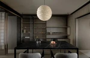 A minimalist dining room featuring a black marble table and fabric upholstered chairs.