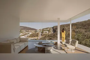 A minimalist residential interior with a view of hills through glass walls.