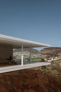 Modern building with glass walls overlooking a scenic landscape.