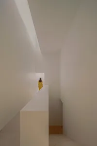A minimalist modern interior featuring a concrete staircase with light streaming through a window.