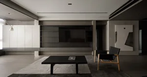 A modern, minimalist living room featuring concrete walls and black furniture.