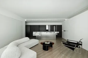 Modern living room with minimalist design, featuring concrete walls and flooring.