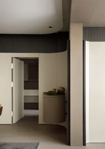 A modern minimalist apartment entrance with a wooden column and a round wooden bin.