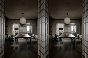 A minimalist living room with a sleek, black dining table, upholstered chairs, and a paper lantern hanging above. The space f