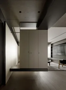 Modern apartment interior with dark wood paneling and white cabinet doors.