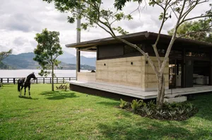 A modern house with a concrete exterior and glass windows overlooking a landscape.