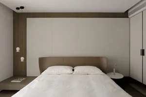 Modern minimalist bedroom with grey and taupe color scheme, featuring a simple bed and soft textiles.