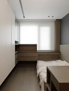 A modern minimalist bedroom featuring wooden cabinets and a bed.