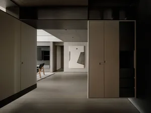 A modern minimalist hallway featuring concrete flooring and wooden cabinets.