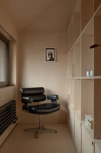 A minimalist home office with a black chair and wooden shelves.
