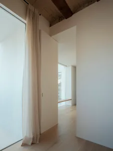 Interior space featuring minimalist design with wooden flooring, glass window, and white walls.