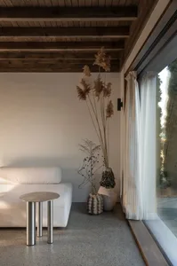 Minimalist living room featuring a white sofa and dried plants in a vase.