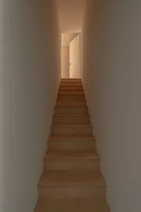 A minimalist staircase made of wood with a warm light at the end.