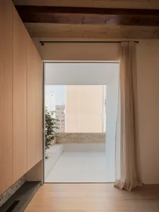 A minimalist white room with a view of a terrace.