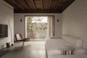 Modern living room with concrete floor, leather armchair, and upholstered sofa.