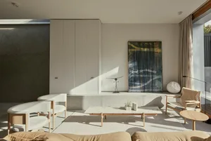 Modern living room featuring minimalist design with concrete walls, a large abstract painting, and a combination of white and