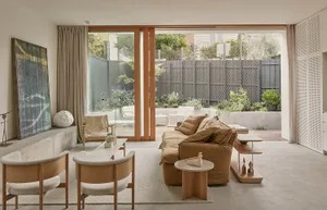 Modern living room featuring a concrete floor, wooden furniture, and a large open space leading to an outdoor area.