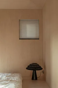 Minimalist bedroom with a black lamp and wooden walls.