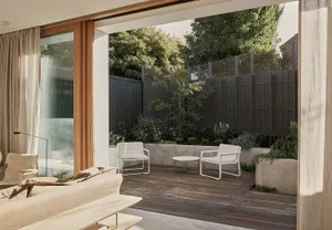A modern patio with concrete flooring, plants, and furniture.