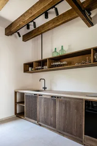 Industrial kitchen with wooden cabinets, green bottles on shelves, and black sink faucet
