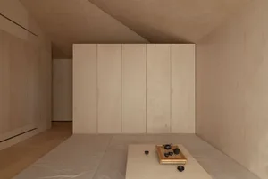 A minimalist bedroom with a white bed and wooden walls and floor.