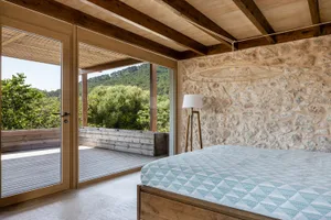 Modern bedroom featuring stone walls and wooden flooring and furniture.