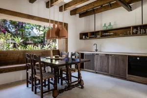 A modern industrial kitchen dining room with wood and concrete materials, featuring a wooden dining table, wooden chairs, bri