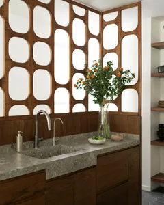 A modern kitchen with a marble countertop featuring a sink, faucet, and decorative items like a vase of flowers and a bowl of