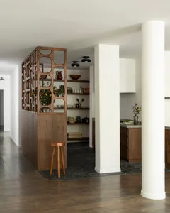 A modern kitchen with an open space design and wooden features, including white cabinets and brown wooden accents.