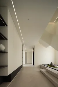 A modern living room featuring a concrete floor, a black coffee table with candles and objects, a black desk with a blue chai
