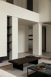 Modern living room featuring a black leather ottoman, marble coffee table, and stone and steel elements.