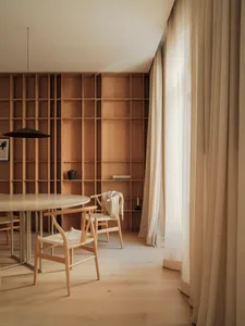A modern minimalist library interior with wooden shelves and a round table.